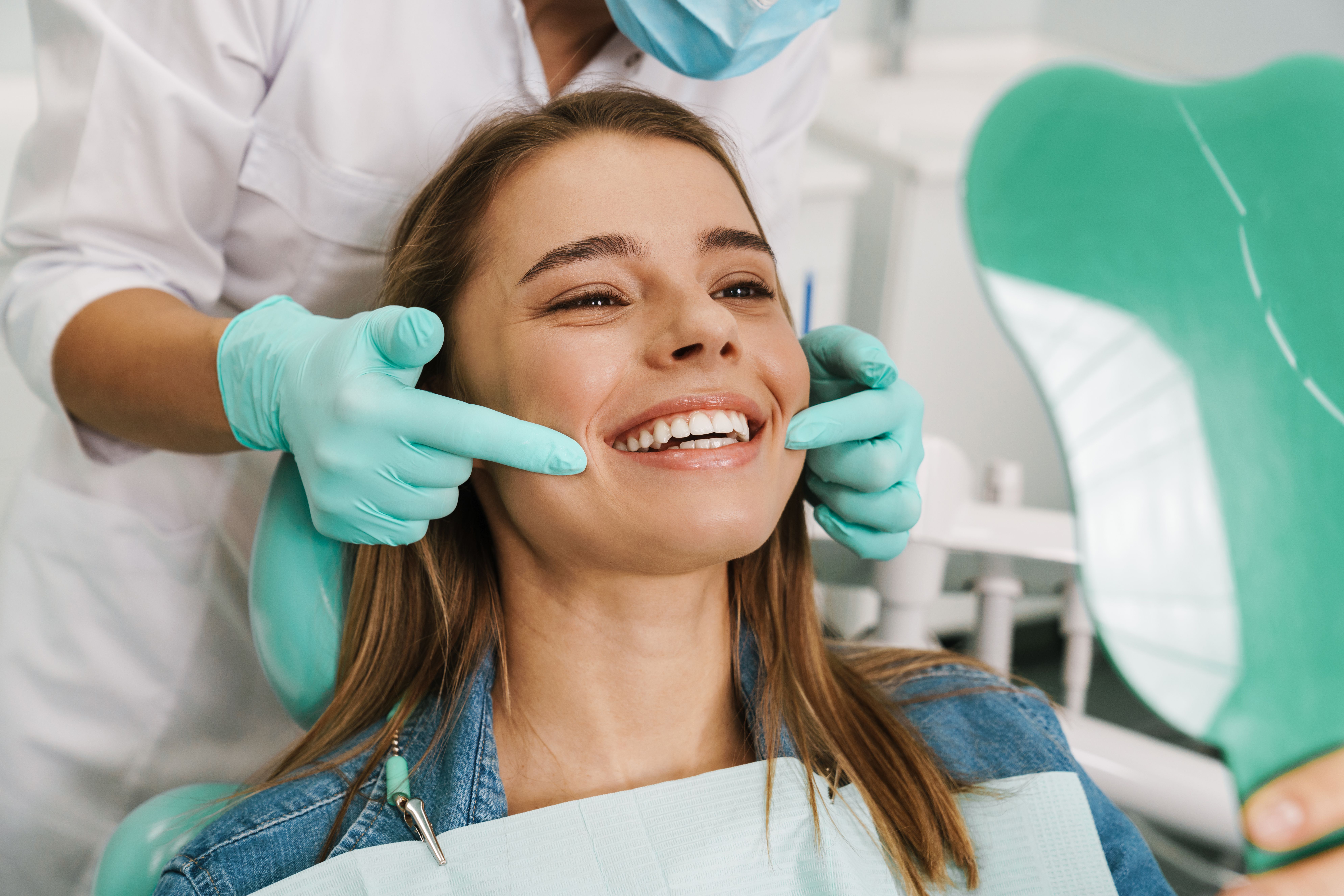Patient viewing her smile in a mirror after dental care